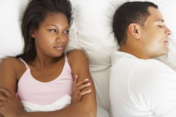 birth control side effects couple in bed with lady looking morosely at the man who is sleeping peacefully
