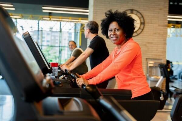 Treadmill Training Benefits - smiling lady of African origin in orange tracksuit top