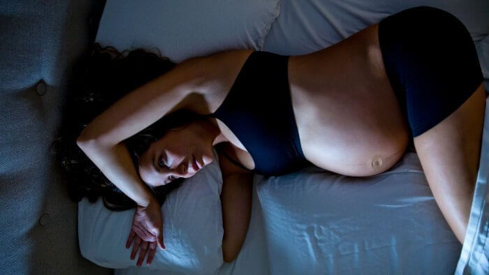 Half naked pregnant lady staring at the ceiling wondering how to get better sleep