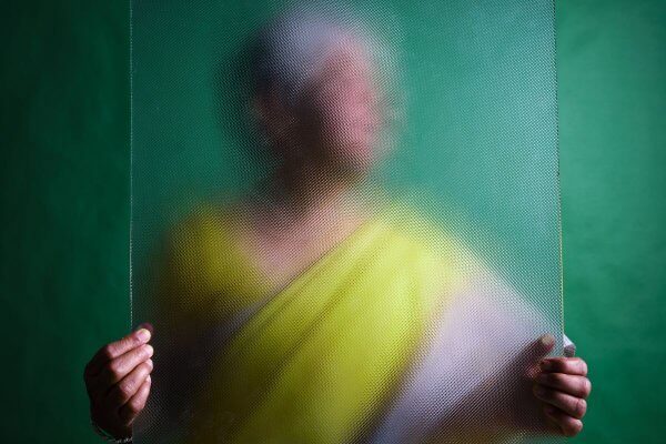 Dementia insight can be difficult - lady in green sari behind a blurred glass