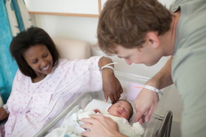 Couple looking over new born baby - mum recovering from vaginal bleeding after childbirth