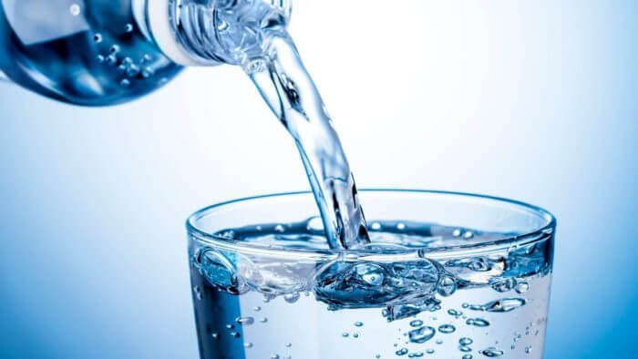Clean water being poured into a glass cup from a bottle