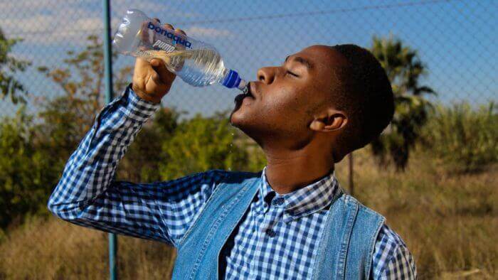 African man with low cut hair drinking water from a bottle