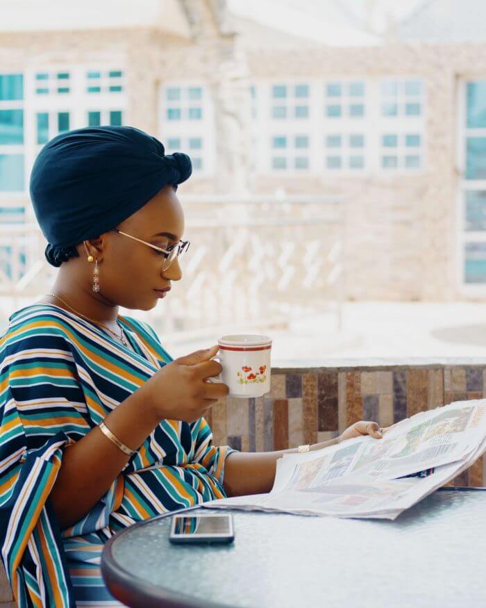 African lady reading a paper and sipping a drink, ectopic pregnancy can happen in a woman of child bearing age.
