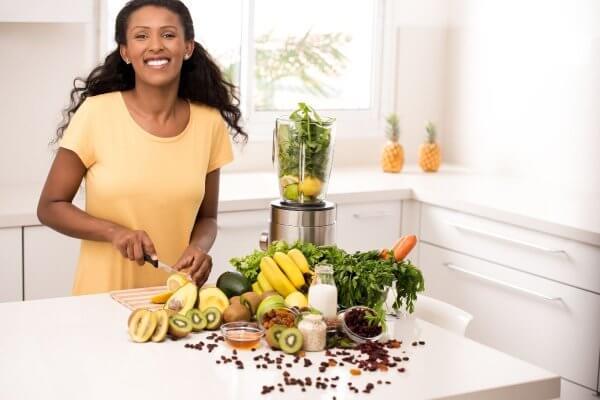 Black lady cutting up veggies and fruit is a healthy lifestyle goal