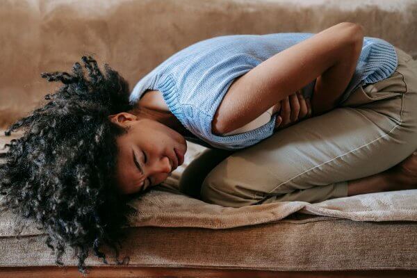 Lady of African origin holding her abdomen in pain from indigestion 