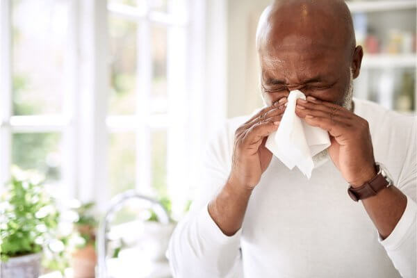 man with cold blowing his nose - Vitamin C doesn't cure it