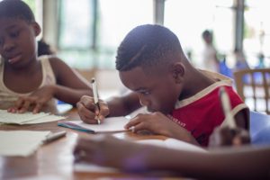 A young boy and girl  of African origin writing at a desk - a children's emergency can happen with no warning!
